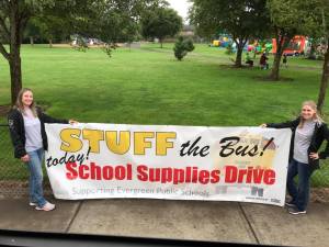 Staff members holding a supply drive banner